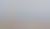 Gothic-style church with a tall spire, surrounded by a town and hills in the background under a cloudy sky.