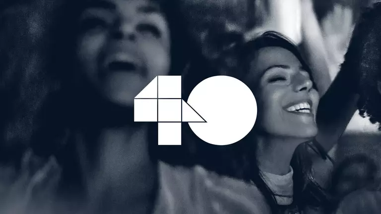 Two women smiling and enjoying themselves, with a large "40" logo prominently displayed in the center.