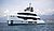 Luxury yacht anchored in calm waters, featuring a sleek white design and multiple decks, with mountains in the background.