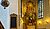 Altar with intricate carvings and religious figures, surrounded by stained glass windows and candle sconces in a church interior.