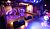 A music performance space featuring stage monitors, a drum set, and colorful lighting effects on the floor.