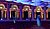 Hanging sound speakers in a concert hall, with ornate architecture and illuminated columns in the background.