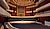 Concert hall interior featuring a wooden stage, rows of seating, and a prominent organ in the background.