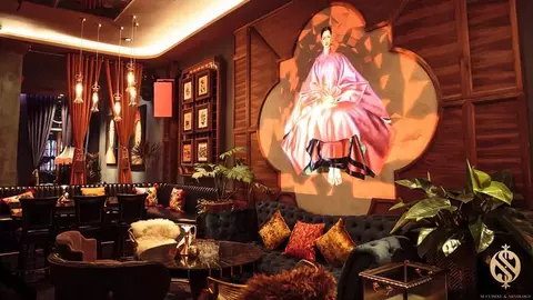 Stylish restaurant interior featuring plush seating, decorative pillows, and a prominent wall art piece of a figure in traditional attire.