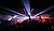 Crowd at a nightclub with vibrant laser lights and raised hands, creating a lively atmosphere.