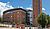 Red brick building with a curved roof and tall tower, featuring large glass windows and signage for the Royal Birmingham Conservatoire.