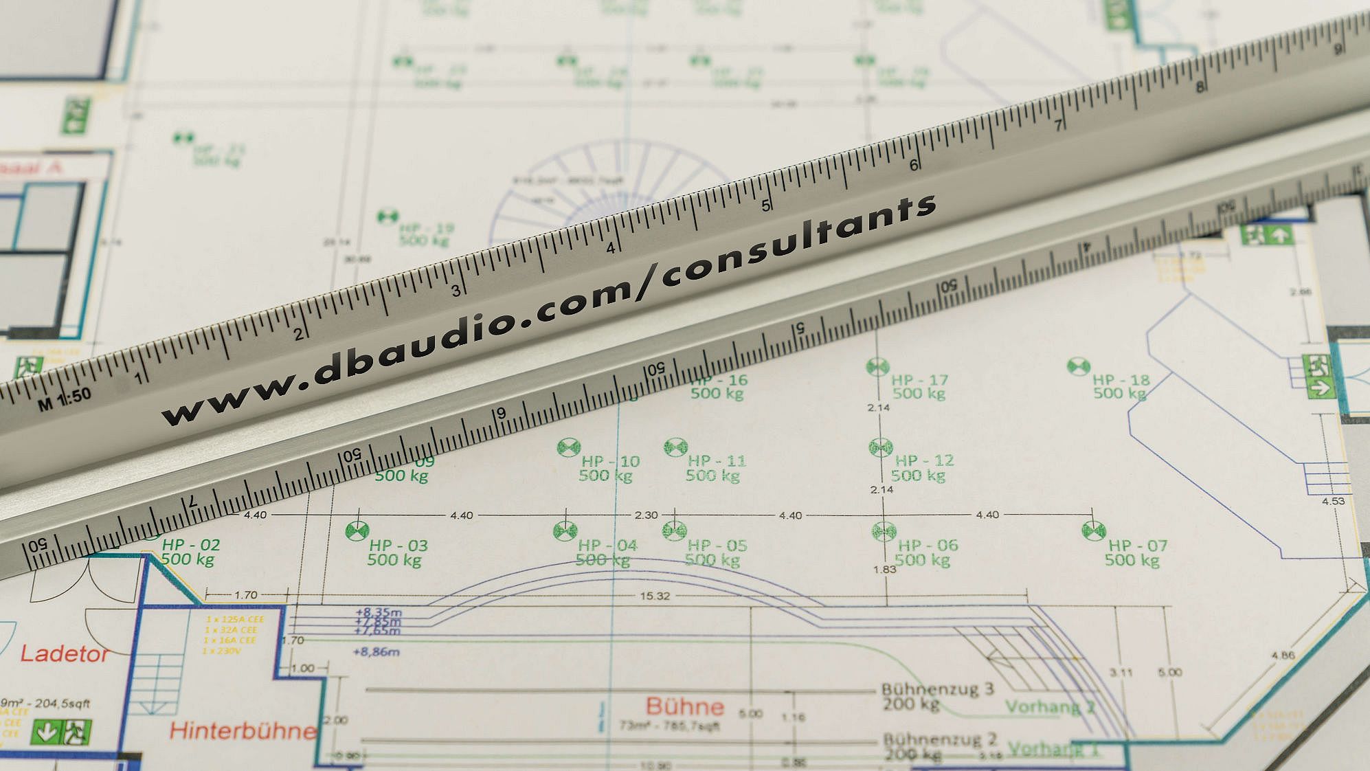 Blueprint featuring detailed measurements and annotations, with a ruler placed across it. The design includes various labeled sections and symbols.