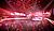 A large crowd enjoys a concert in a vibrant arena, illuminated by colorful lights and visual effects.