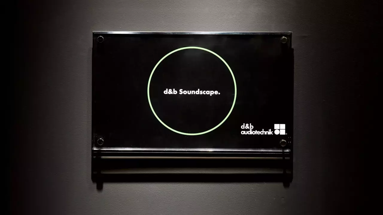 Sign displaying "d&b Soundscape" with a circular graphic, mounted on a dark wall. Includes d&b audiotechnik branding.