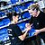 Two women in black shirts collaborate at a workstation, handling tools and materials, with blue storage bins in the background.