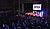 A live improv performance on stage with a large audience, featuring a banner that reads "DROPOUT IMPROV."