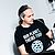Man wearing a black t-shirt with the text "OUR PLANET, THEIRS TOO!" and animal silhouettes, seated at a desk with trophies in the background.