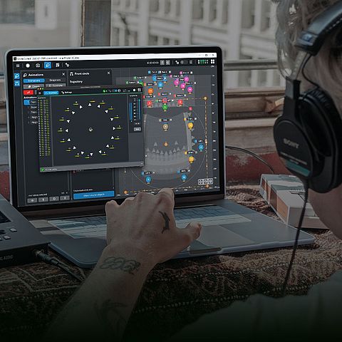 A person wearing headphones interacts with music production software on a laptop, featuring a circular visual display and audio equipment nearby.