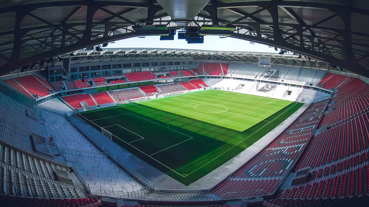 Ein Panoramablick auf ein modernes Fußballstadion mit einem gut gepflegten Spielfeld und leeren Sitzbereichen.
