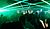 Crowd dancing in a dimly lit venue with green laser lights creating dynamic patterns overhead.
