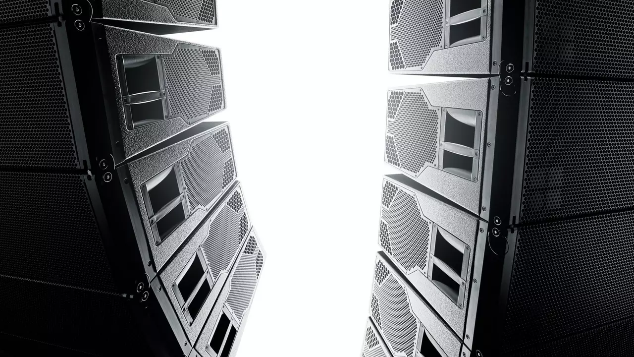 Two large speaker stacks positioned facing each other, creating a narrow gap filled with bright light in the center.