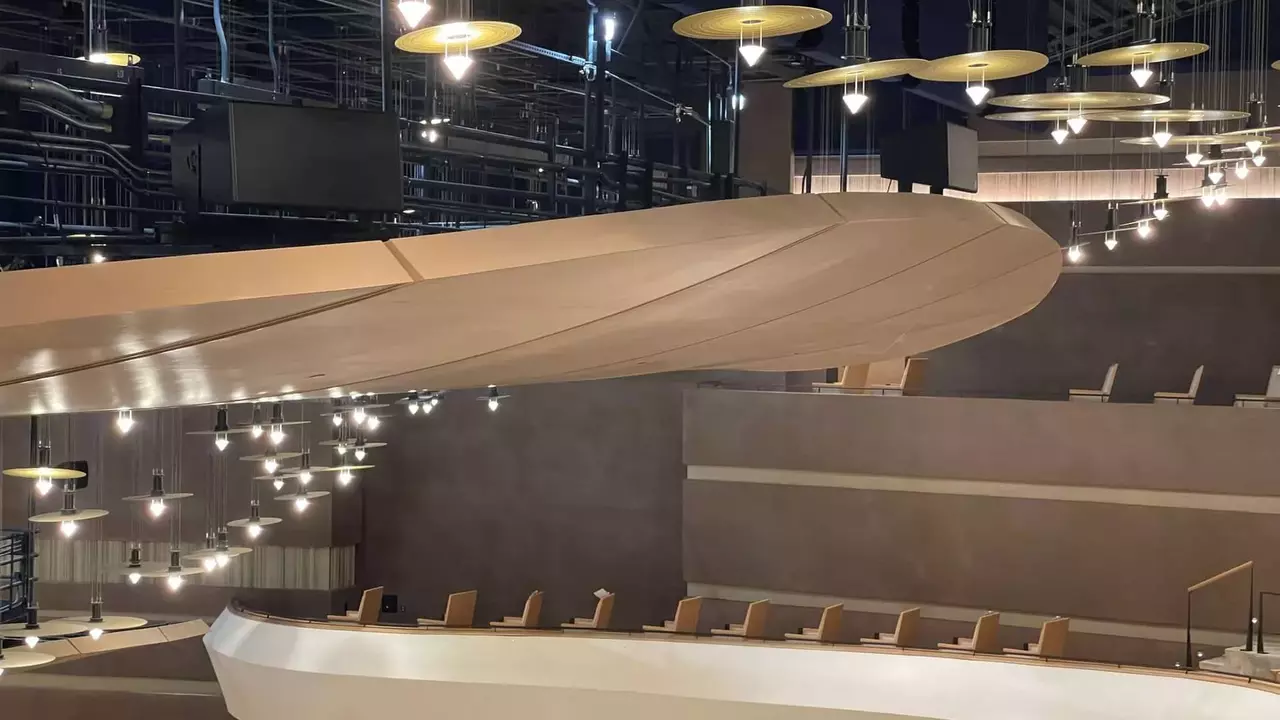 Modernes Auditorium mit einer gewölbten Holzdecke, gestuften Sitzplätzen und dekorativen Beleuchtungskörpern.