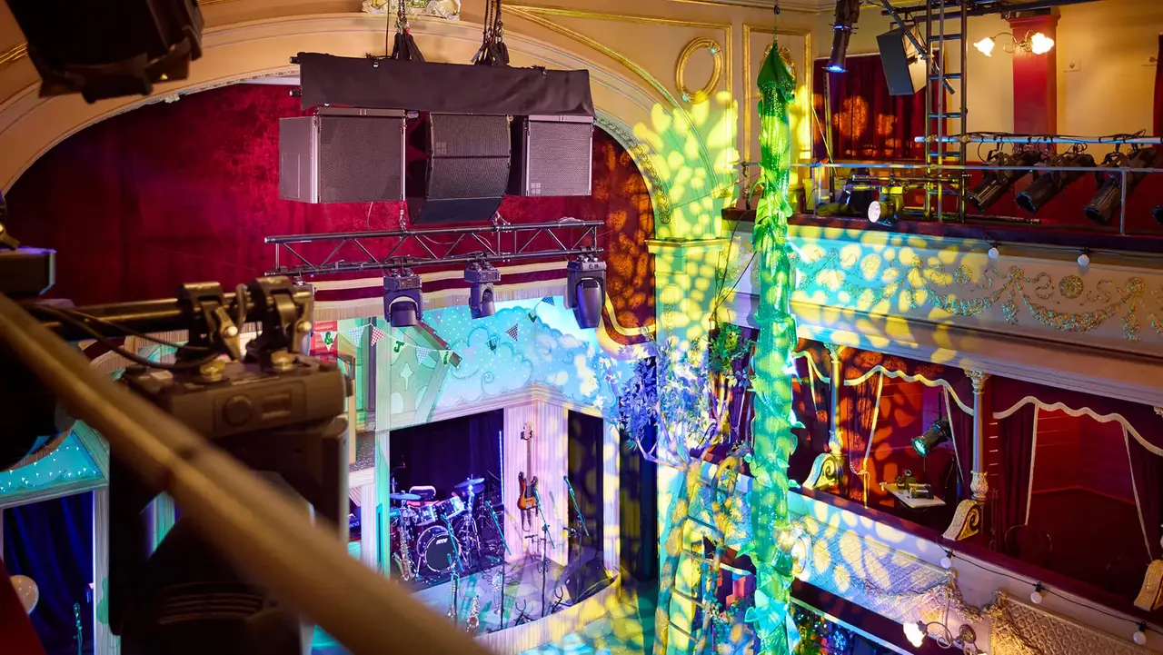 Interior view of a performance venue featuring stage equipment, colorful lighting effects, and musical instruments set up for a show.
