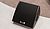 Black audio speaker with a textured grille, designed for sound amplification, positioned on a light-colored surface.