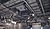 Suspended sound and lighting equipment in a large indoor venue, featuring a grid of speakers and rigging above a seating area.