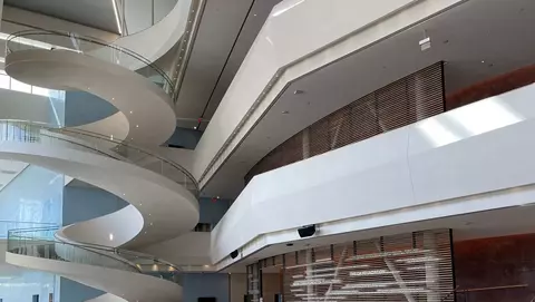 Modern interior featuring a spiral staircase, polished floors, and sleek architectural lines, with large windows allowing natural light.