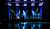 Concert stage with musical instruments, including drums and keyboards, illuminated by blue and green lights.
