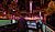 A sound technician operates a mixing console surrounded by colorful lights and festive decorations in a lively venue.