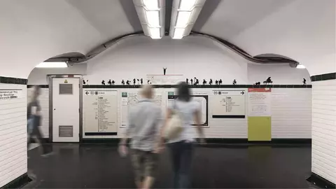 Two blurred figures walk through a subway station, with a tiled wall displaying transit maps and silhouettes of people above.