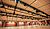 Large indoor venue with a high ceiling, featuring overhead lighting fixtures and wooden paneling along the walls.